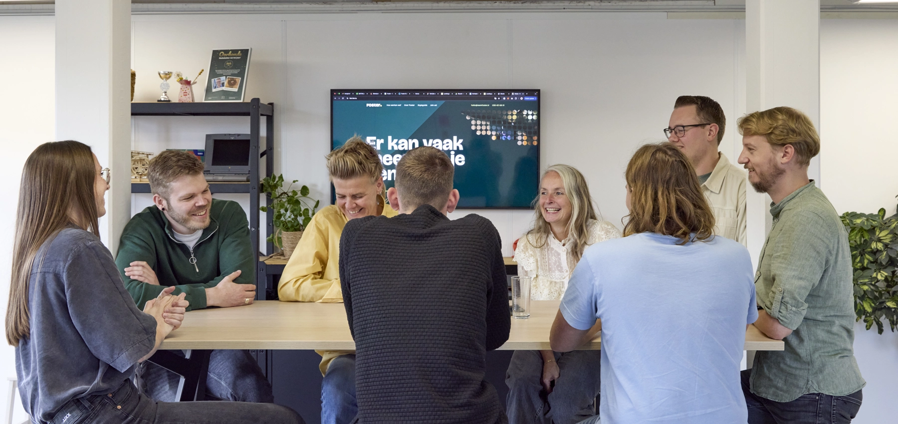 Foto van team Foster, lachend aan de bar in het kantoor
